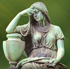 An old statue of a depressed woman leaning on an urn against a green background.